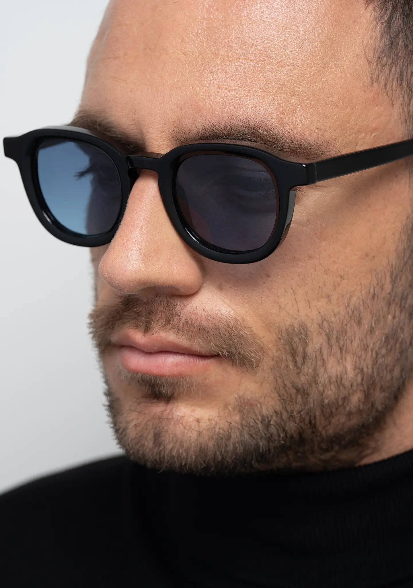 mens sunglasses Bo Bo Noir Narr panto round in shiny black acetate with gradient blue nylon lenses, man wearing, side view.