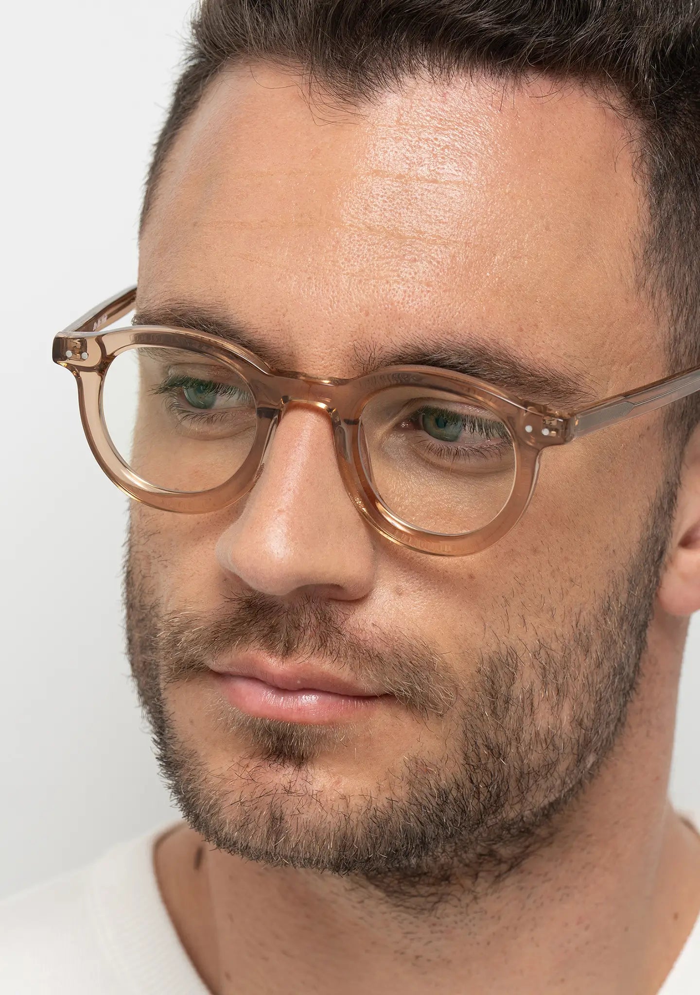 mens Close-up of William crystal peach bold round blue light blocking glasses worn by a man