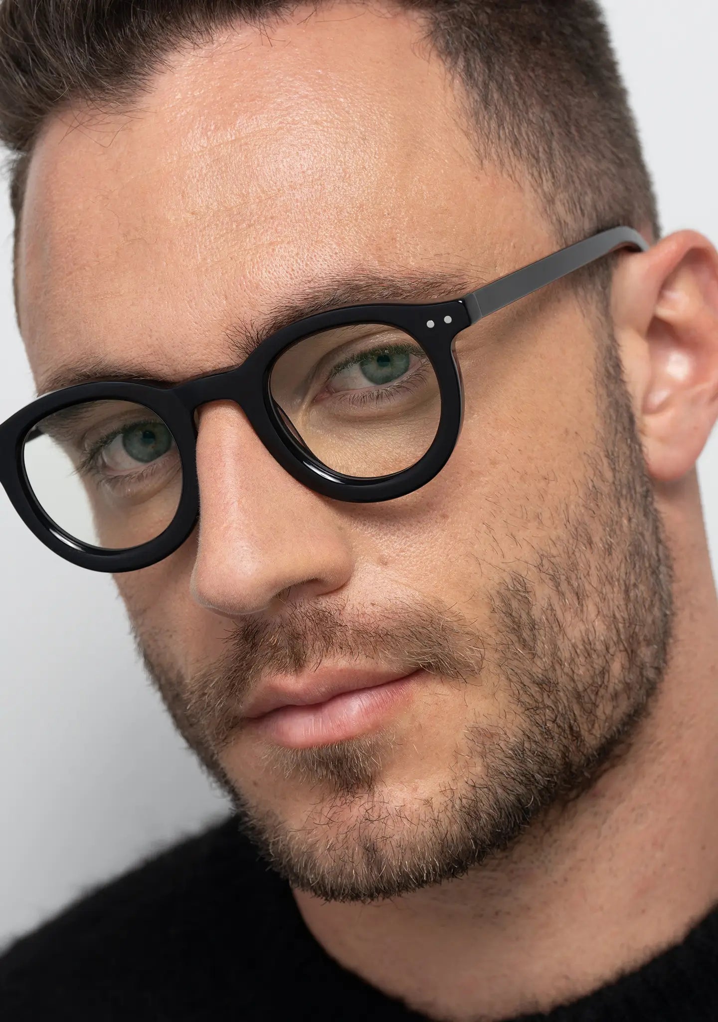 mens William shiny black round optical frame worn by a man close up